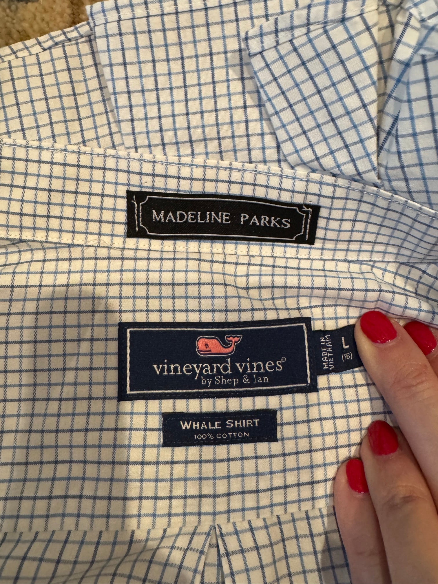 Close-up of a Vineyard Vines by Shep & Ian whale shirt with a blue and white gingham pattern, showing the Madeline Parks label and a hand with red nail polish holding the fabric.