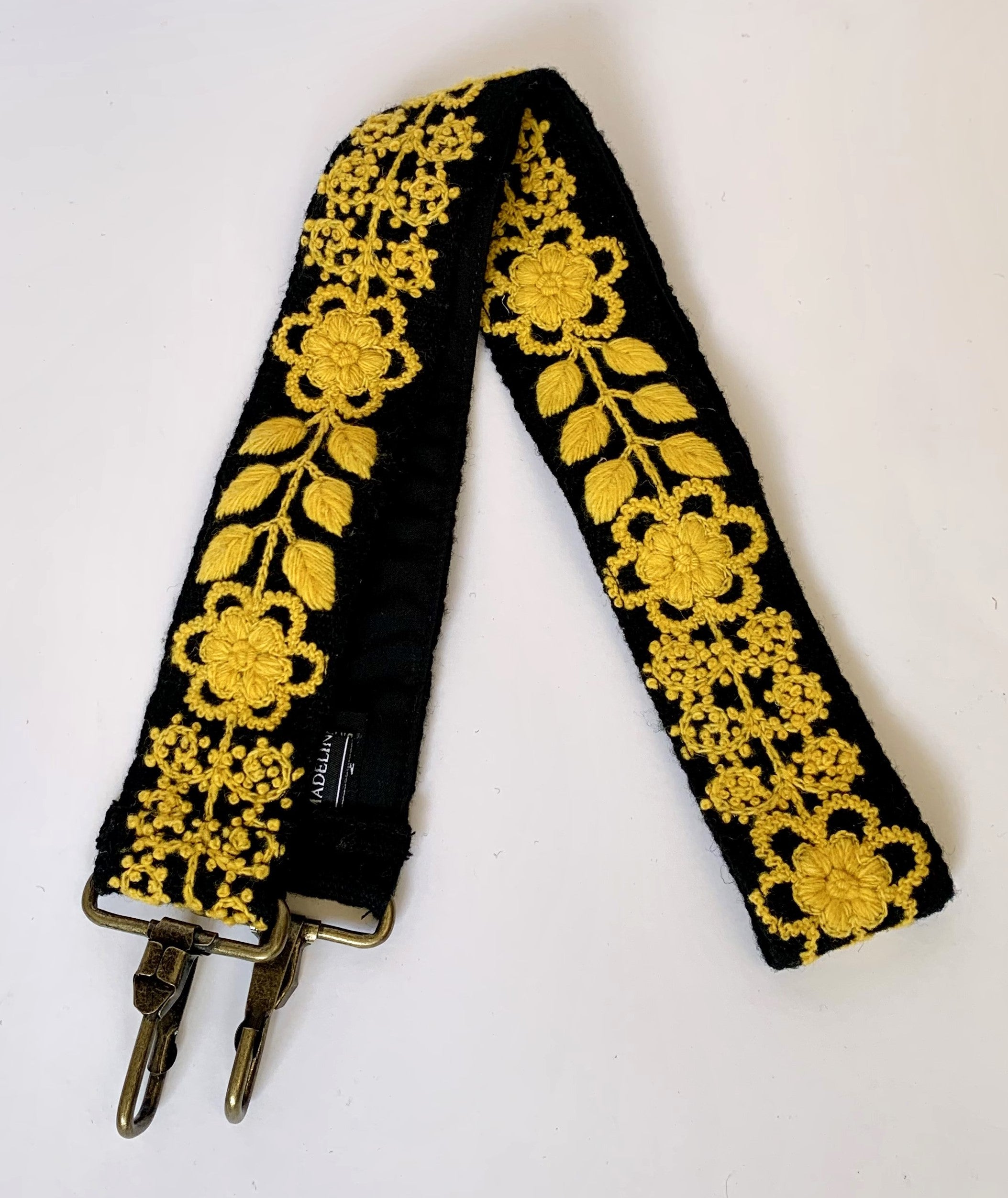 Black and gold strap with hand-loomed wool fabric, featuring gold floral and leaf design. Non-adjustable, pairs perfectly with the Catherine purse. Hand embroidered by Fair Trade artisans in the Andes mountains of Peru.