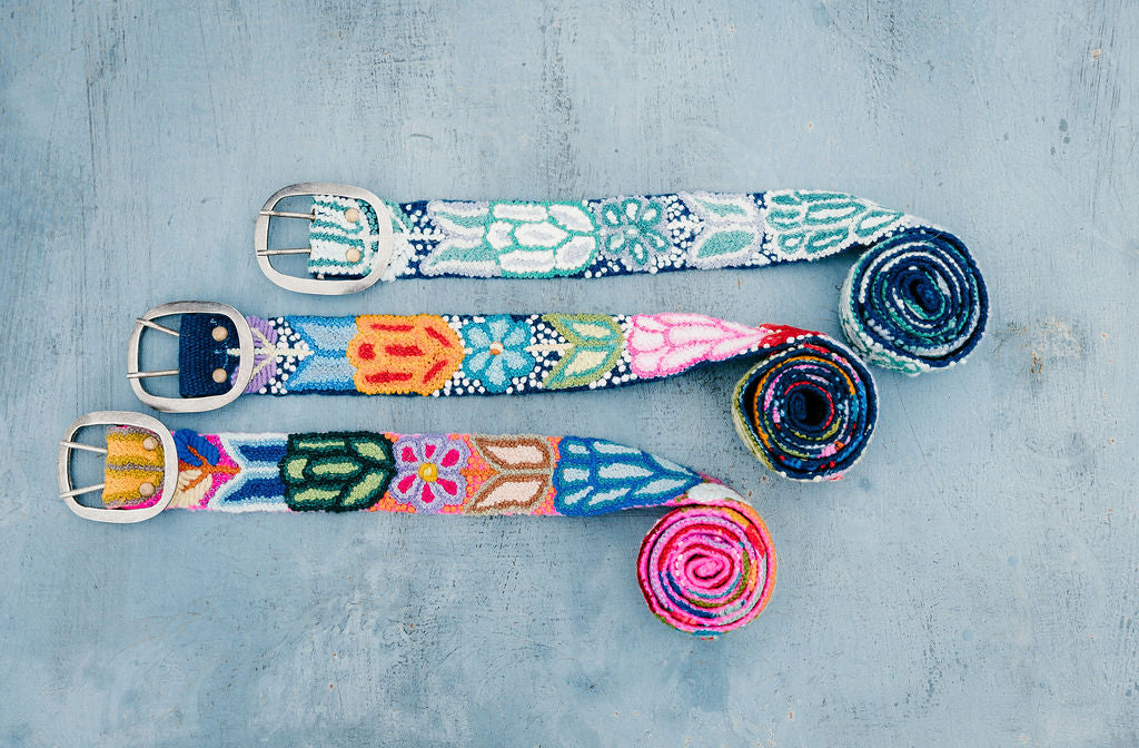 Three colorful hand embroidered belts displayed on a blue background.