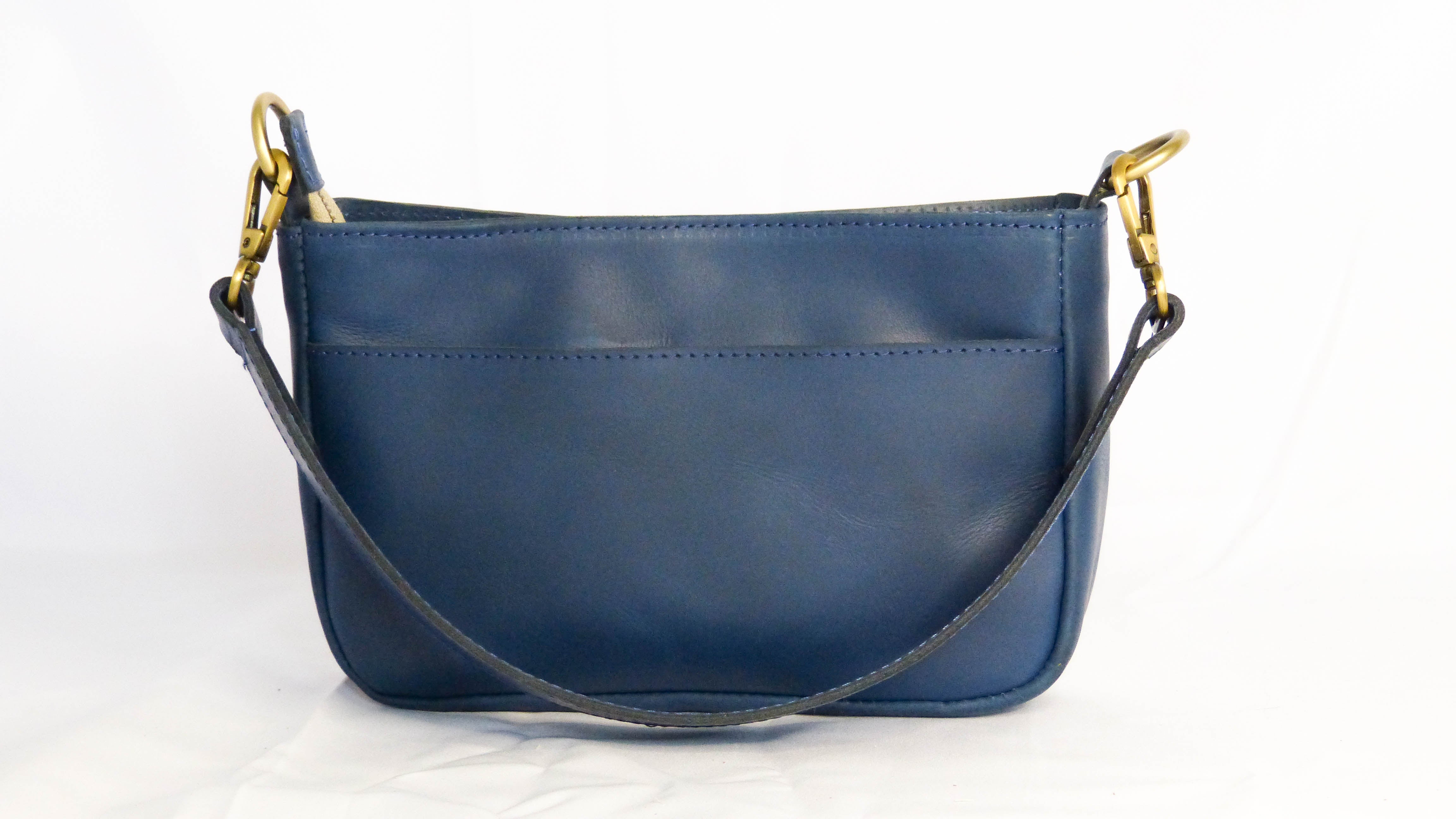 A fair trade Jessica leather purse in cornflower blue with removable shoulder strap. Handmade by Ethiopian artisans, zippered top, inside zipper pocket, and phone pocket. Dimensions: 9 x 5.5 x 2.25.