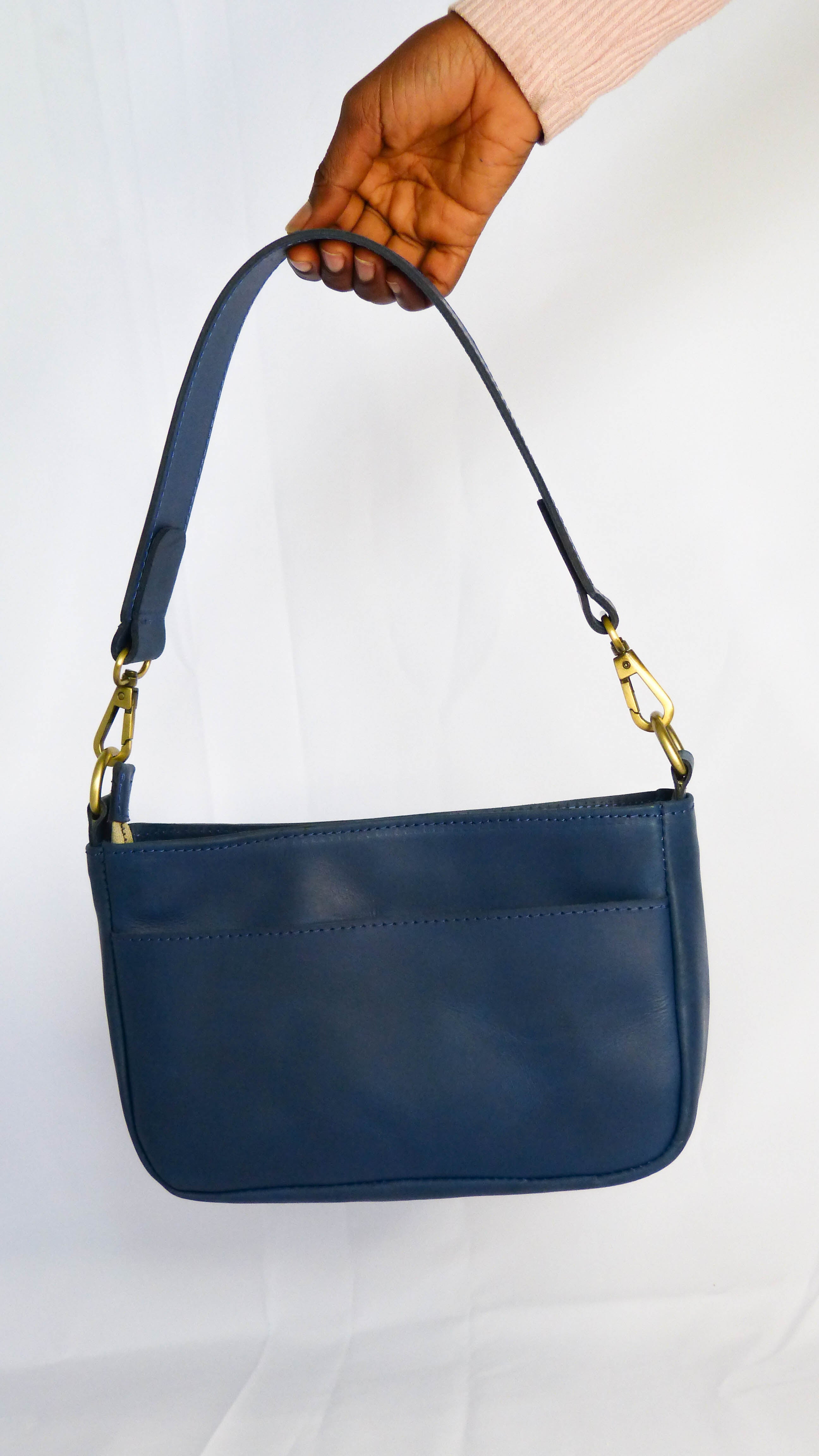 A fair trade Jessica Leather Purse in Cornflower Blue with gold handles. Handmade by Ethiopian artisans, featuring a zippered top, inside pocket, and removable shoulder strap. Dimensions: 9 x 5.5 x 2.25.