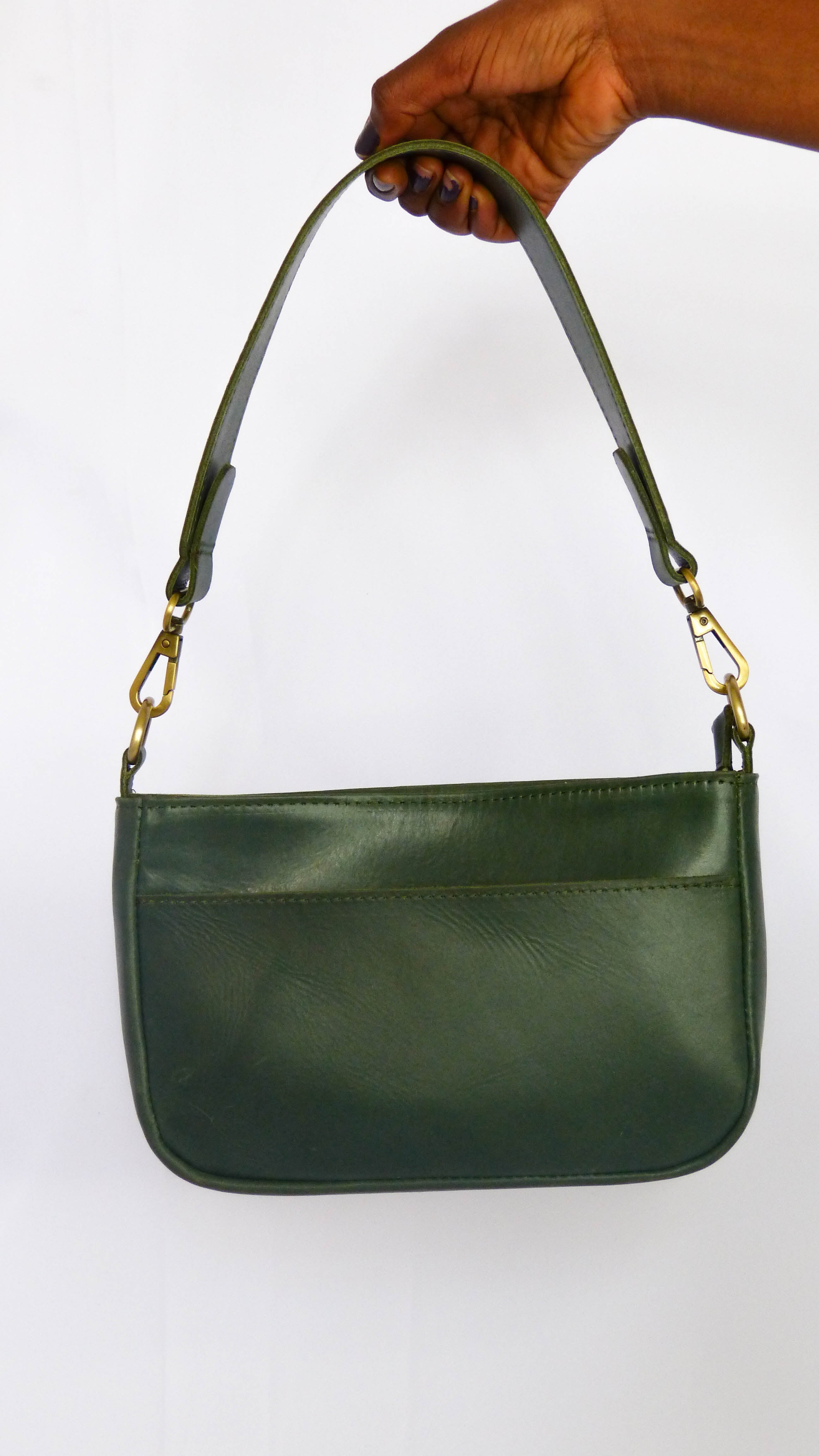 A close-up of the Jessica Leather Purse in Hunter Green, featuring gold handles and a removable shoulder strap. Handmade by artisans in Ethiopia, perfect for everyday use with zippered compartments and phone pocket.
