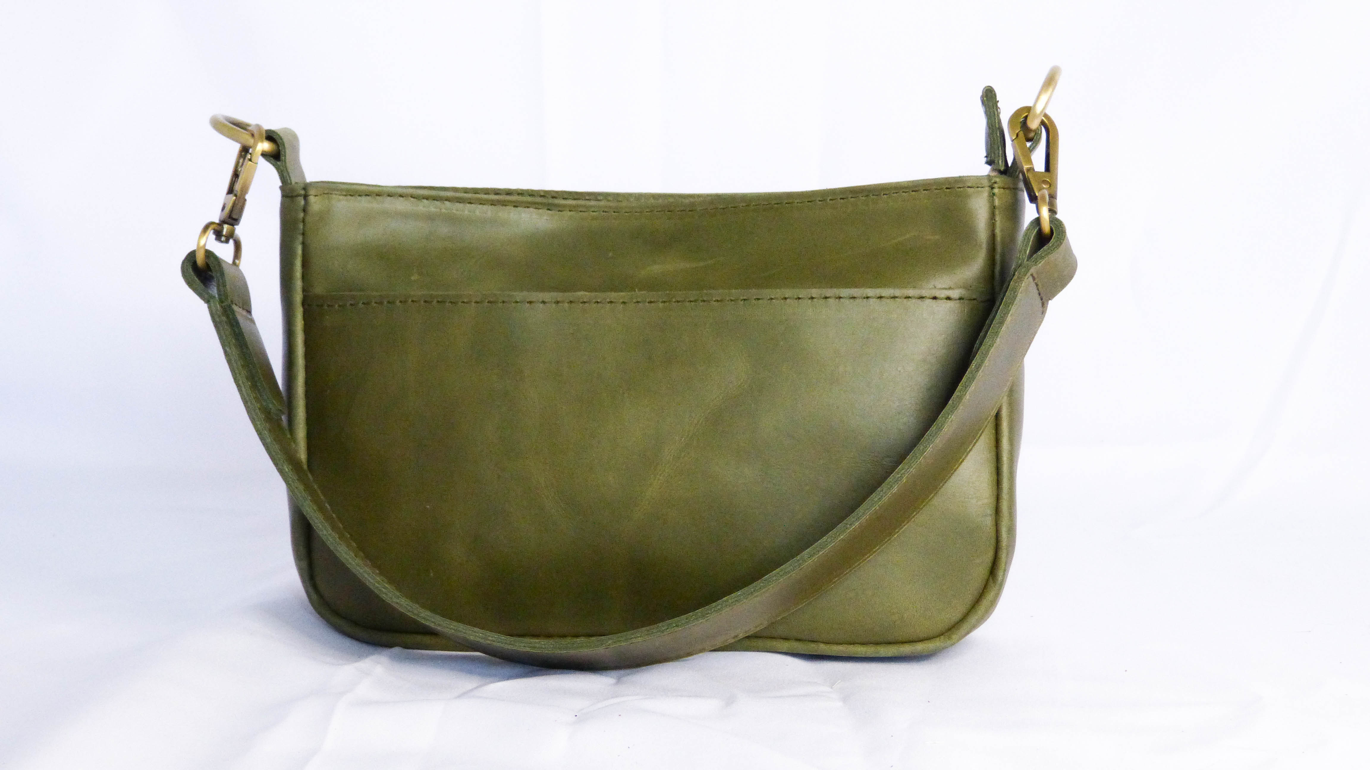 A handcrafted olive leather Jessica purse with removable shoulder strap. Features zippered top, inside zipper pocket, and outside phone pocket. Ethically made by Ethiopian artisans.