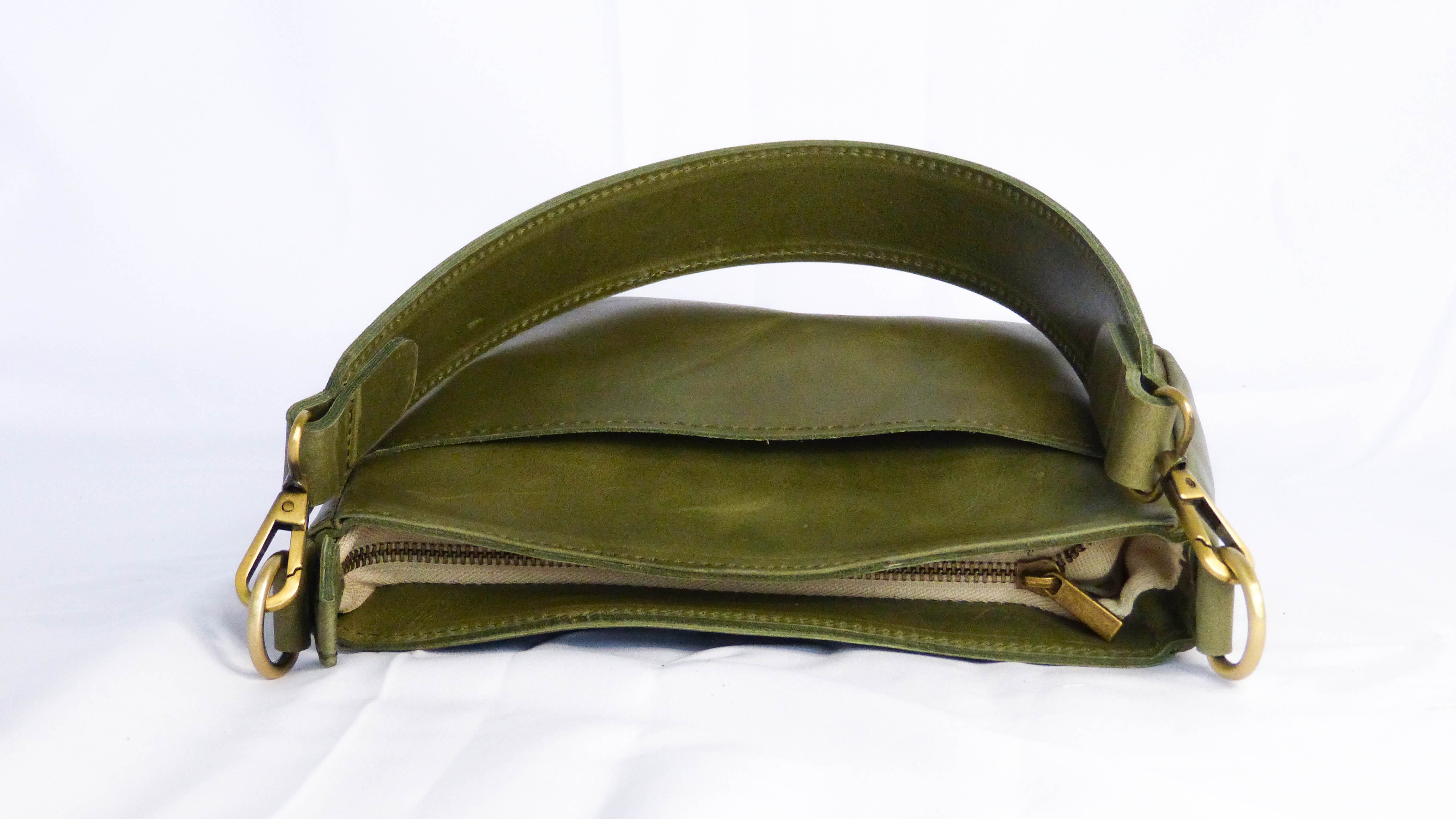A handmade olive leather Jessica purse with a zippered top, removable shoulder strap, and outside phone pocket. Ethically crafted by Ethiopian artisans.