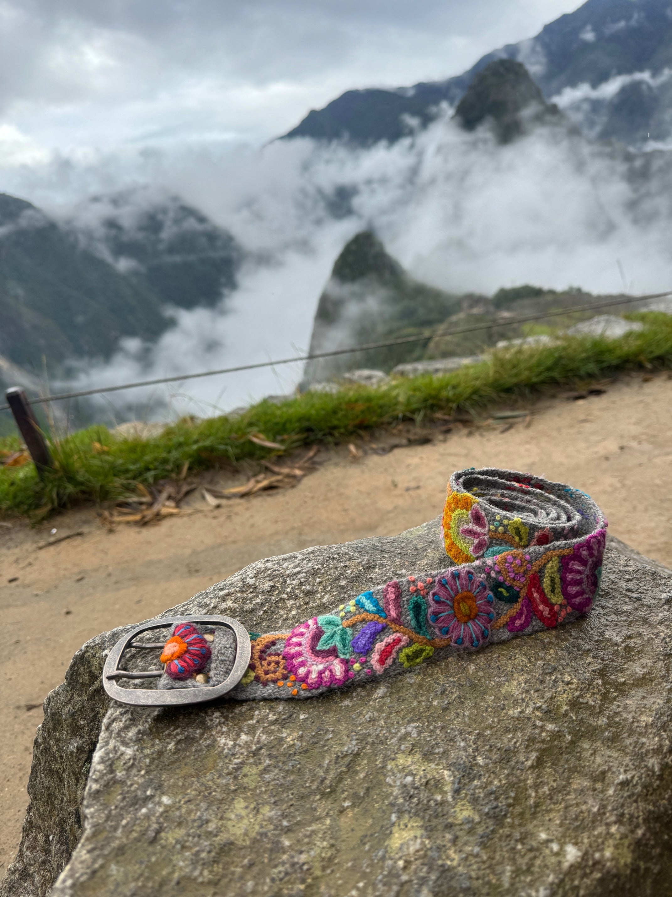 Bright Hand Embroidered Belt displayed on a rock, showcasing vibrant floral patterns crafted by Fair Trade artisans from the Andes Mountains.