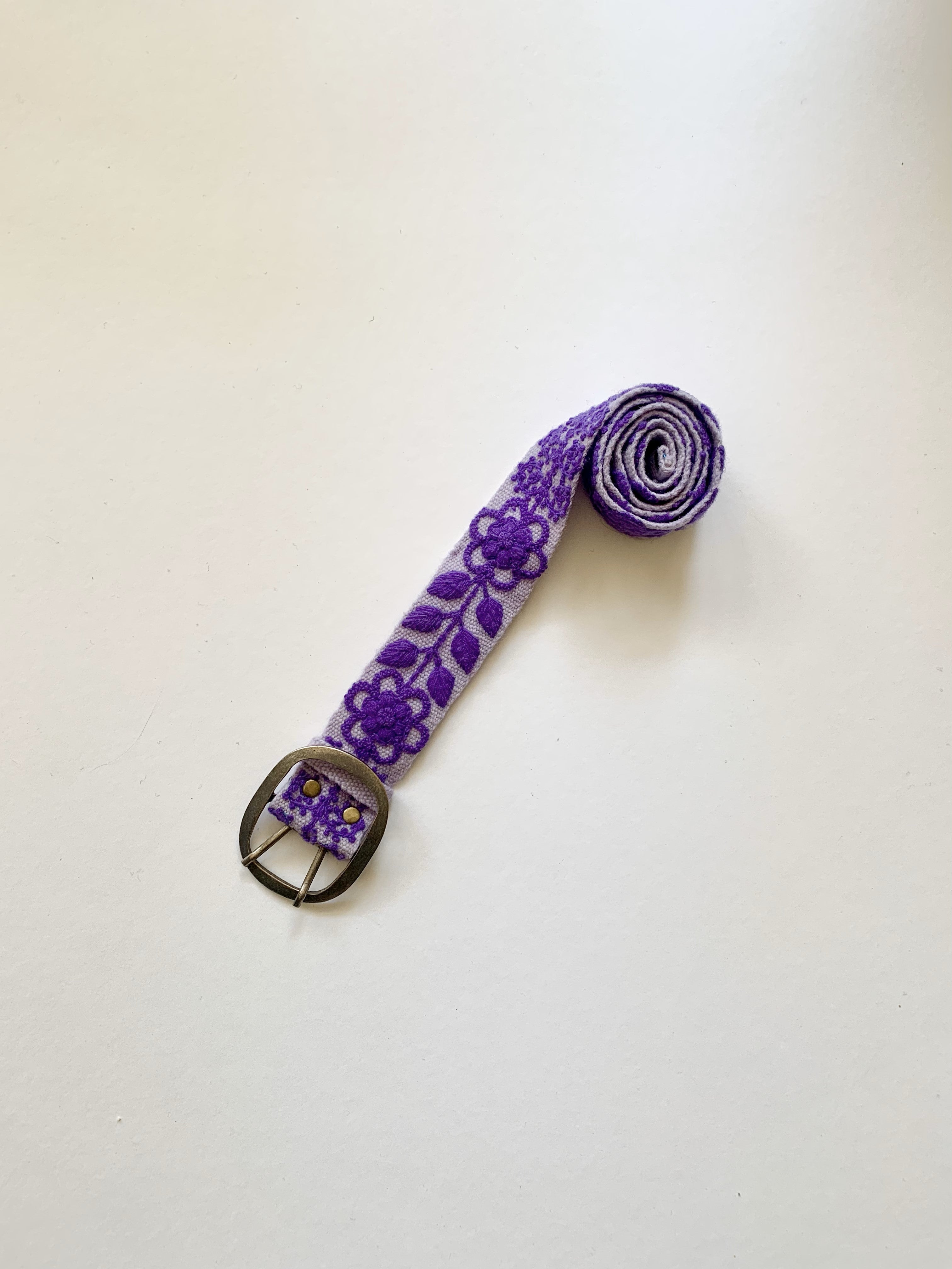 Eliza Embroidered Belt features hand loomed purple wool with floral embroidery and a silver buckle, crafted by Fair Trade artisans in Peru.