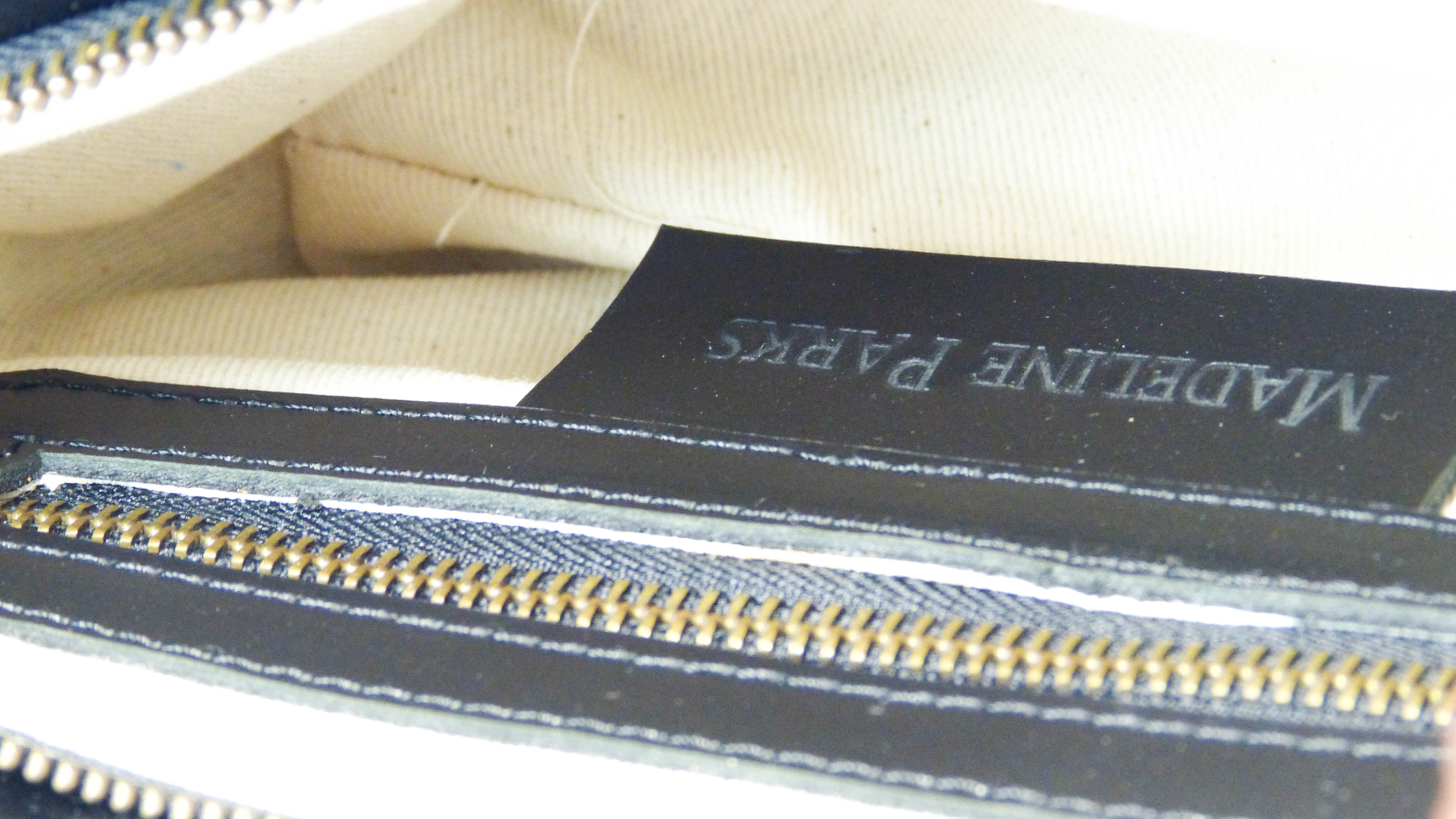 A black leather purse named Jessica, featuring a zippered top, inside pocket, and removable shoulder strap. Handmade by Ethiopian artisans for Madeline Parks Designs.