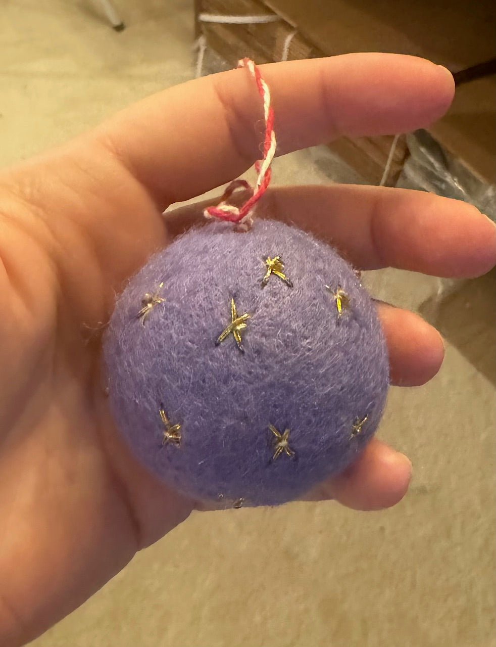 Hand holding a Purple Felt Ornament adorned with gold stars, showcasing artisanal craftsmanship from Madeline Parks ™.