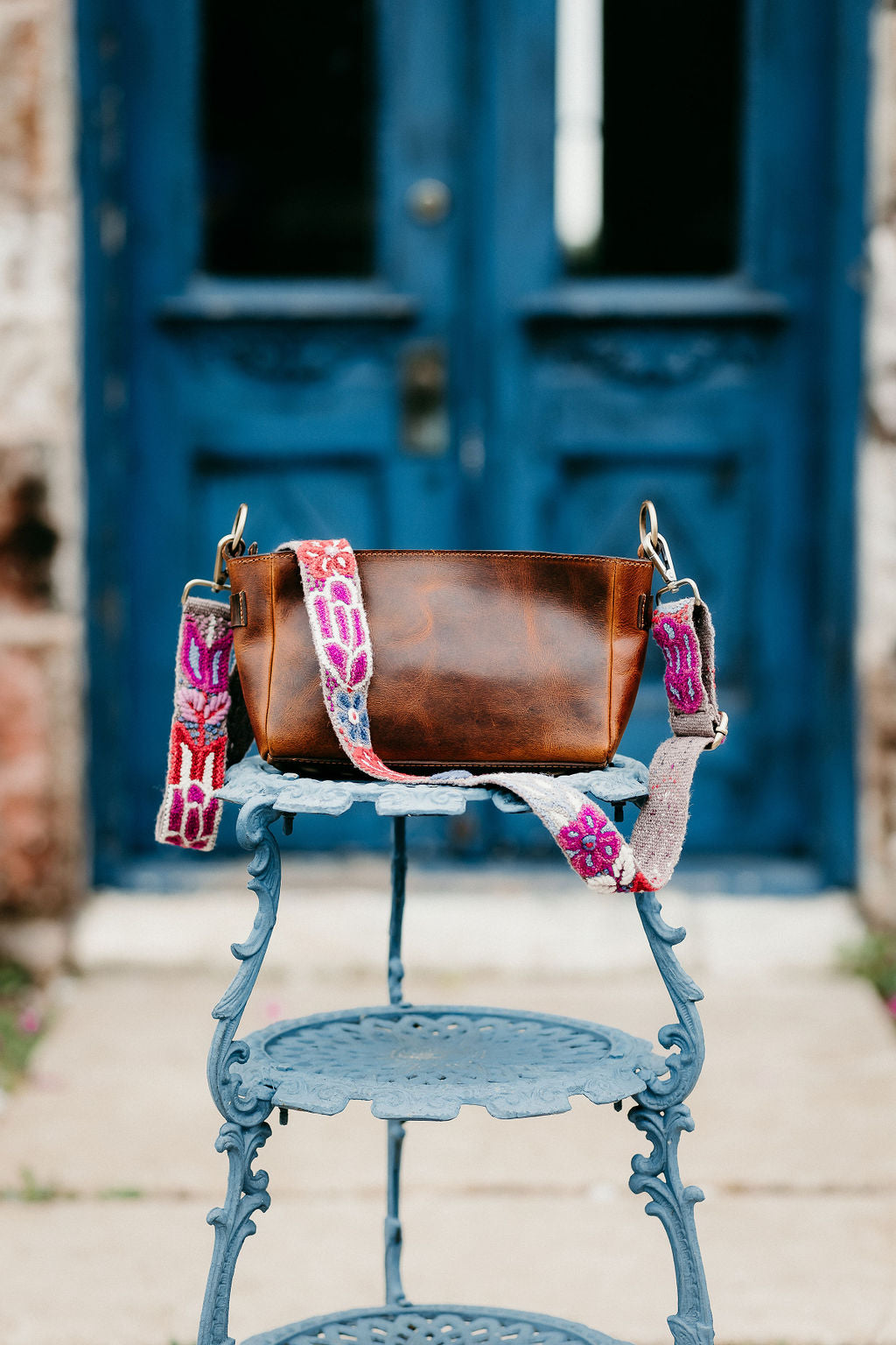 A handcrafted brown purse featuring an adjustable strap.