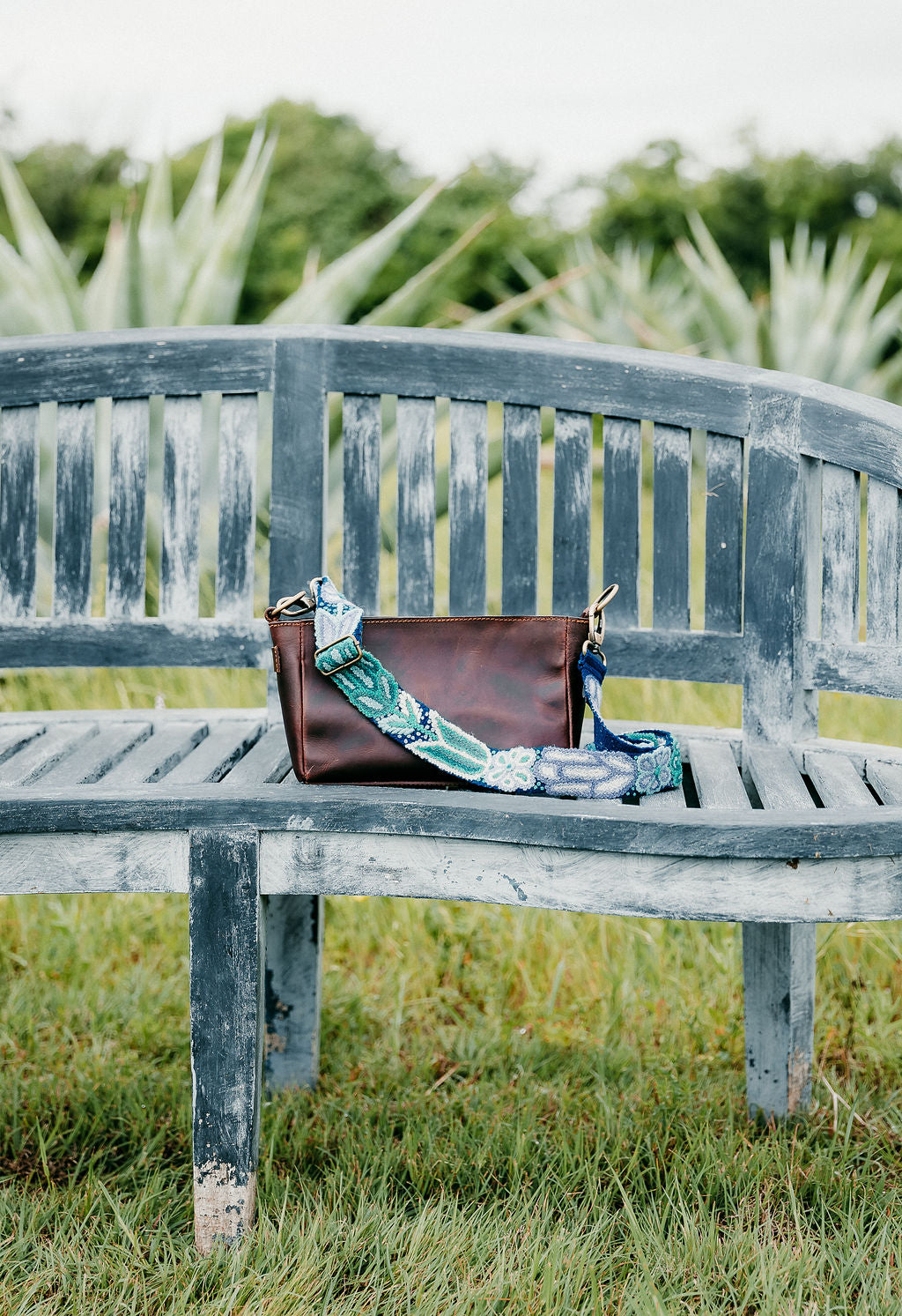 Blues Adjustable Strap on a bench, hand embroidered by Fair Trade artisans in the Andes mountains of Peru. Pairs perfectly with the Dena and Anna purses.