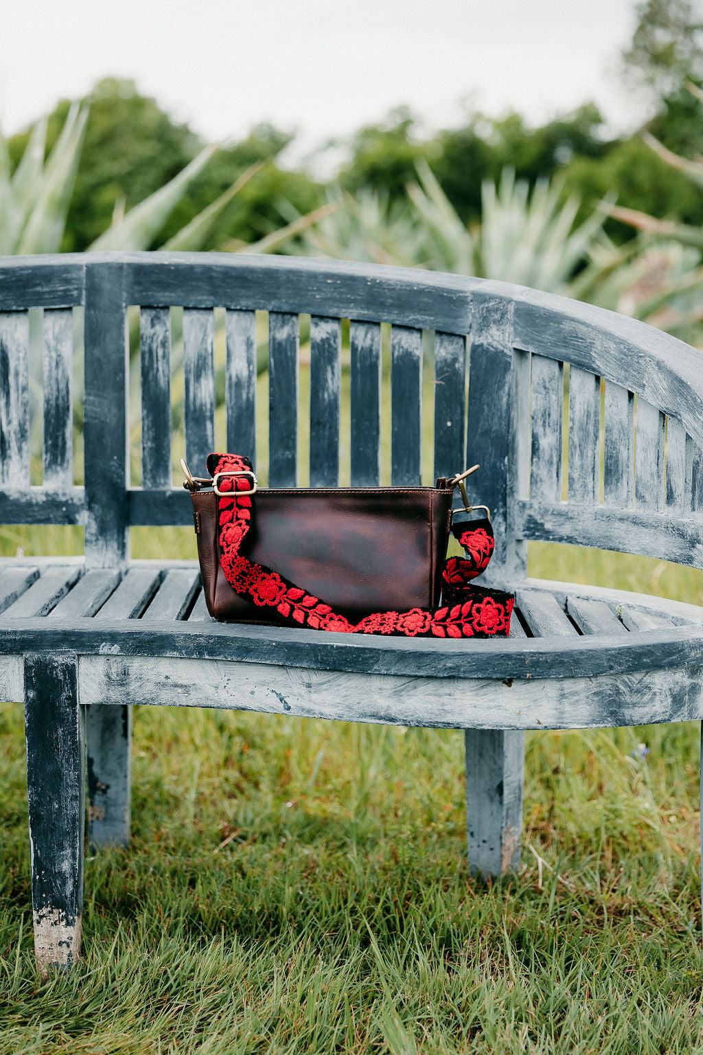 Kennedi Adjustable Strap purse attached to brown leather purse displayed on a bench.