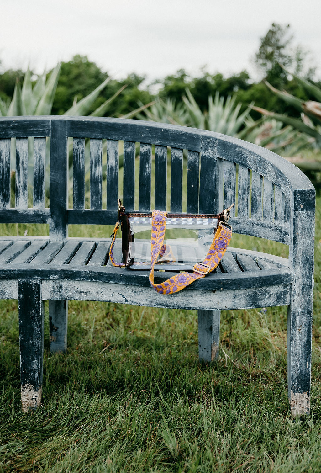 Arden Adjustable Strap hand-woven wool purse strap shown on a bench with a fair trade clear purse.
