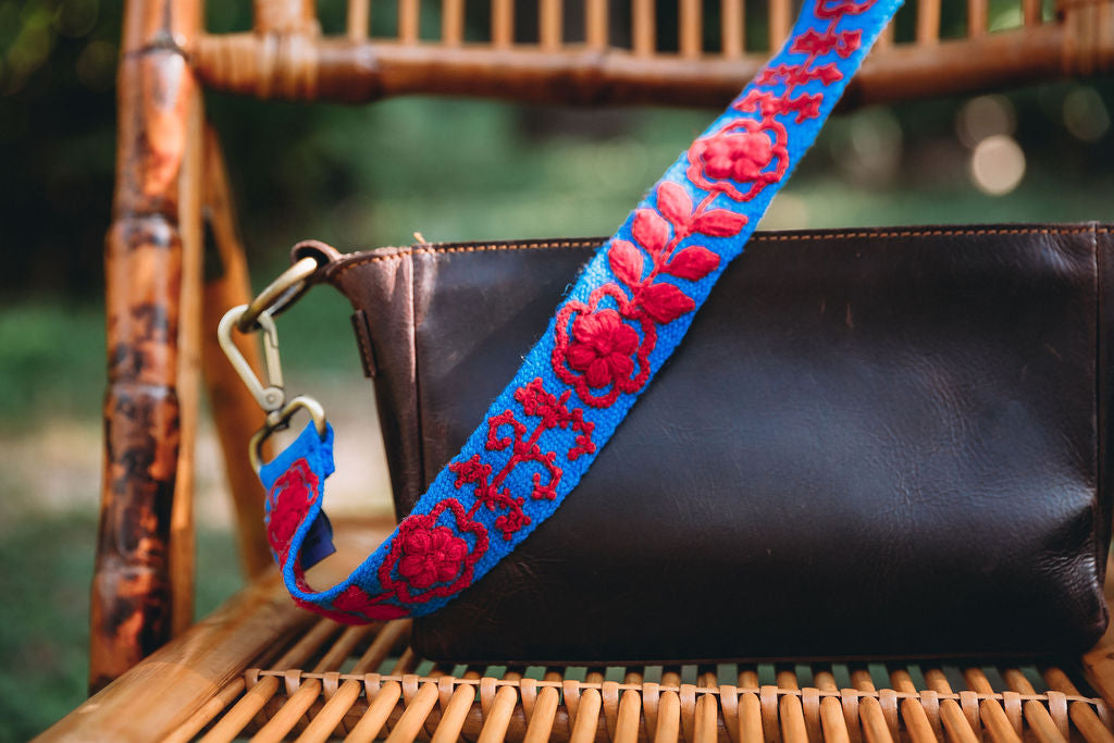 Taylor Adjustable Strap attached to a brown leather purse displayed on a chair.
