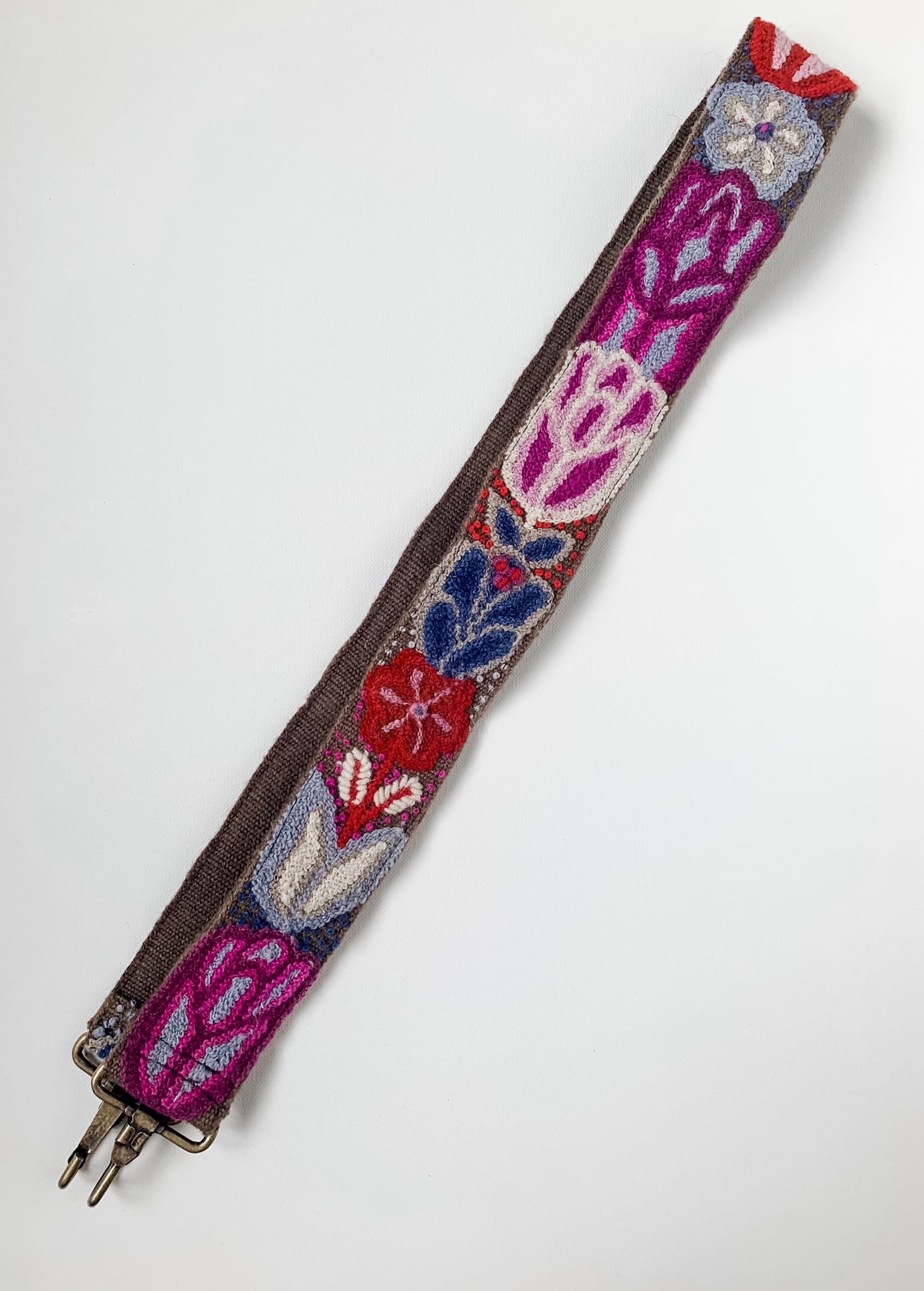 A wool fabric purse strap with red and purple floral accents