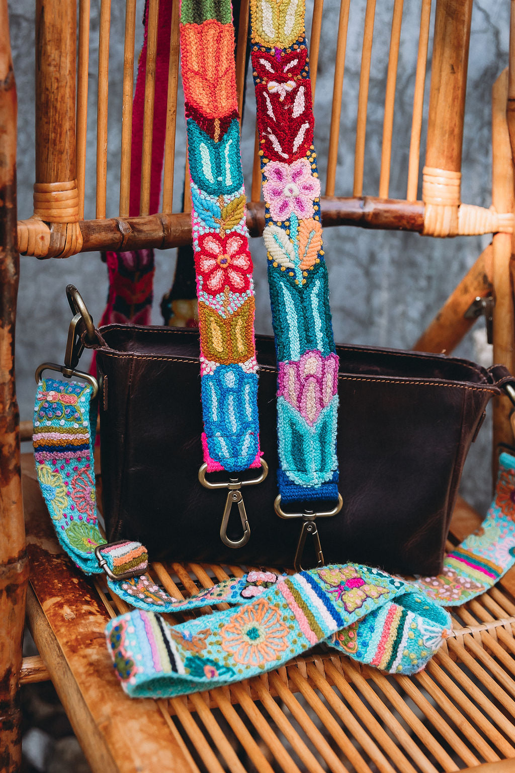 A collection of adjustable hand embroidered fair trade purse straps on a chair.