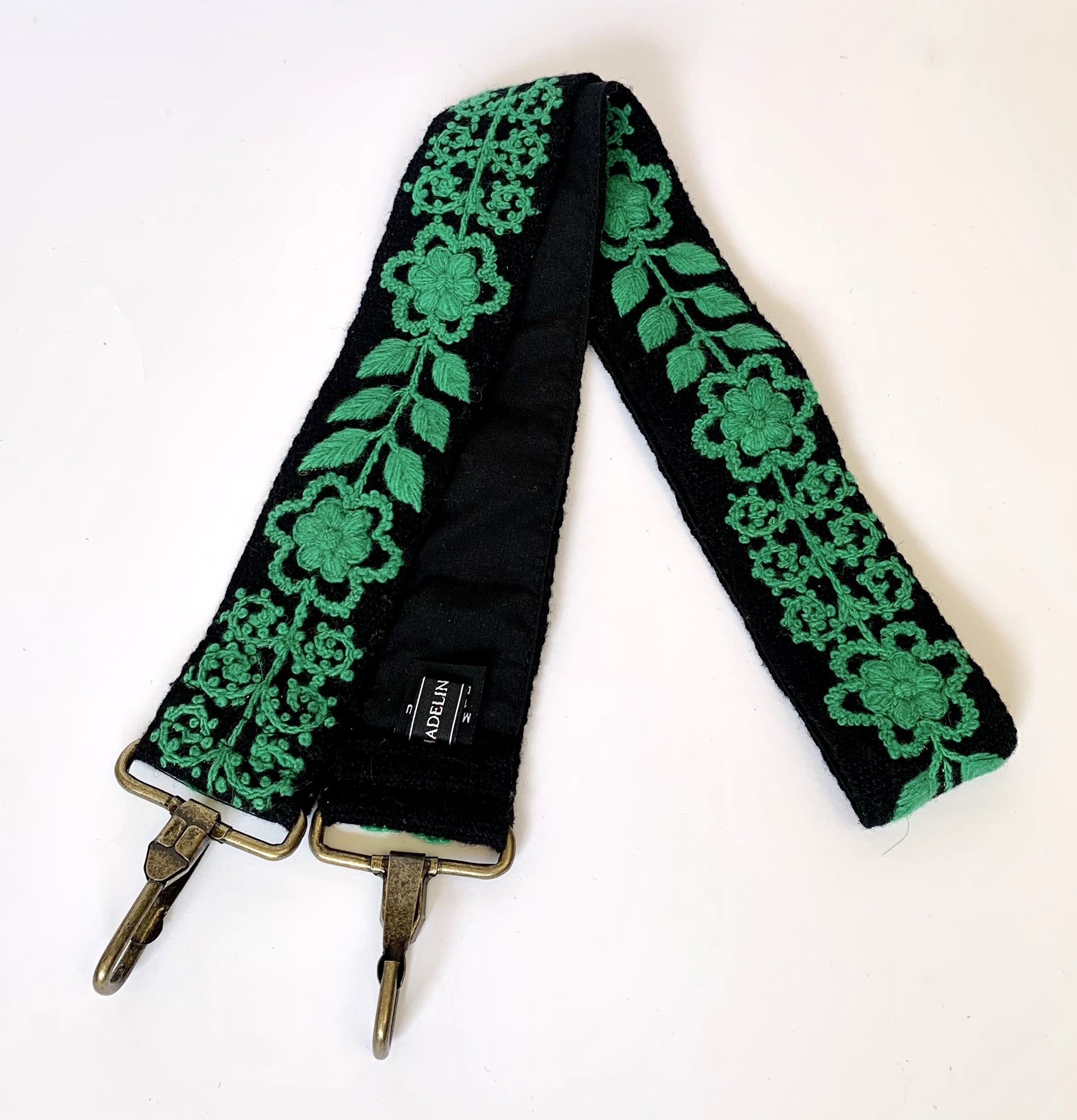 Black and green strap with metal hooks, featuring a floral and leaves design