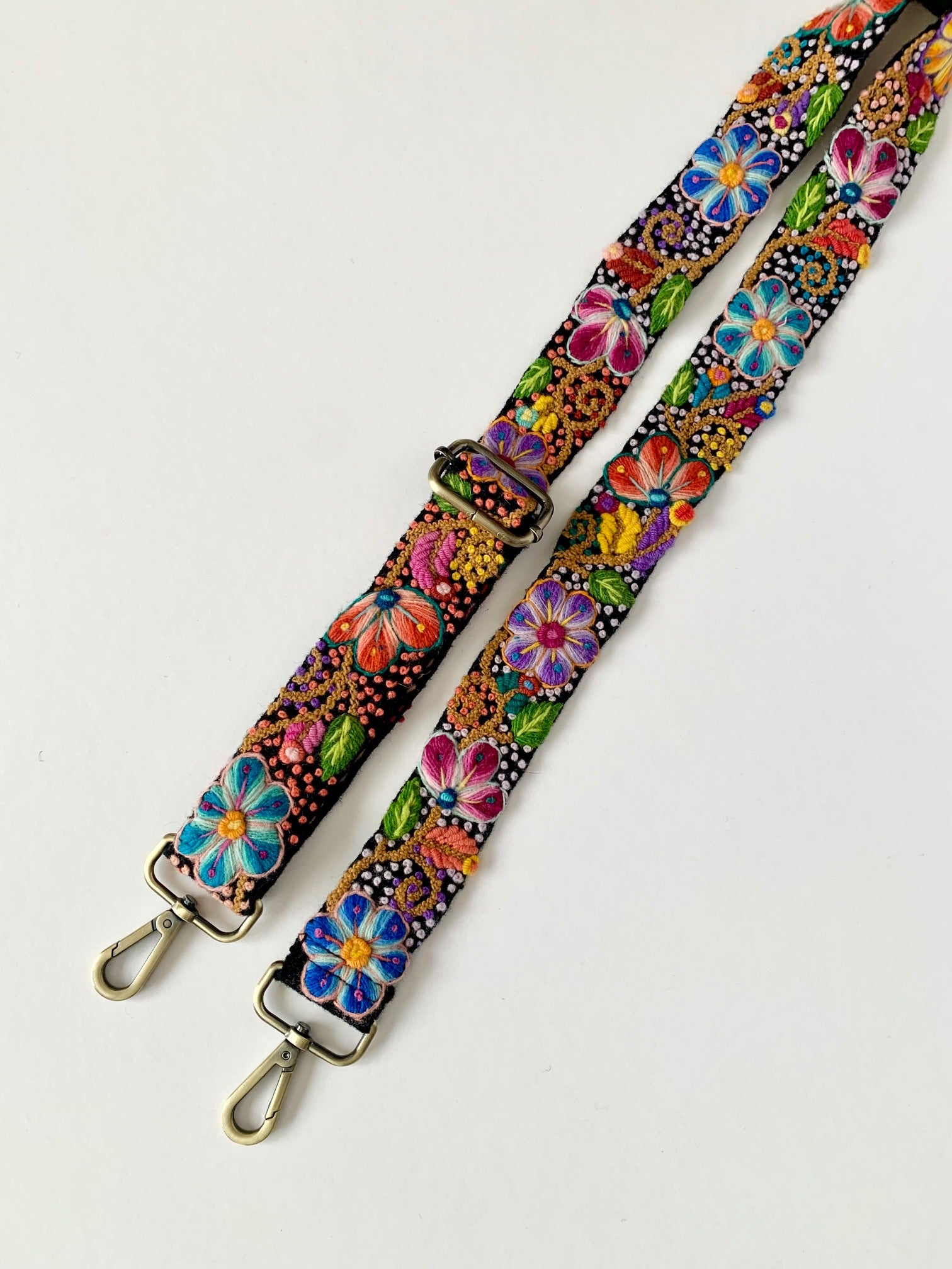 Black Floral Strap with colorful hand embroidery, close-ups of vibrant flowers on fabric straps.