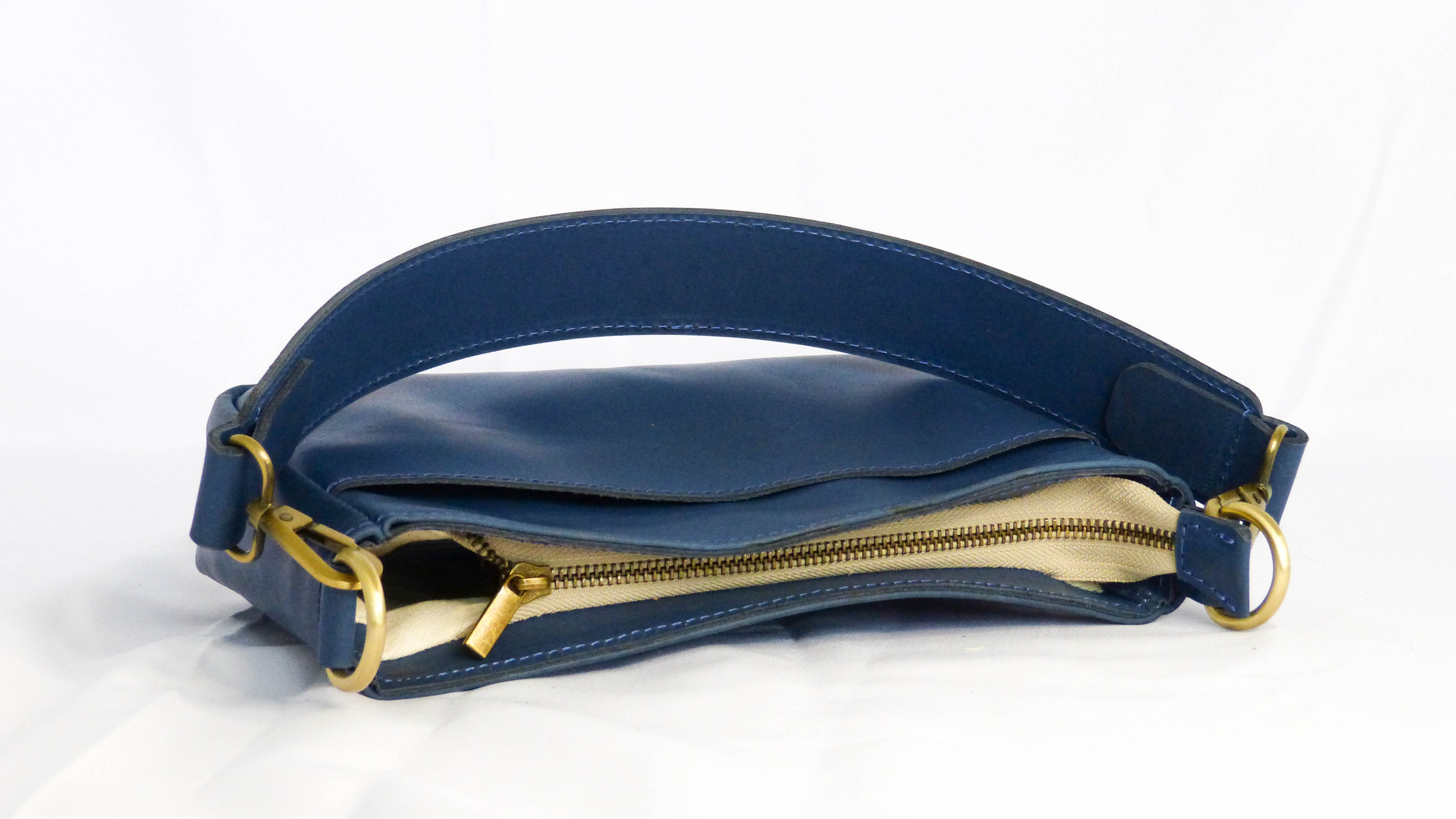 A close-up of the Jessica Leather Purse in Cornflower Blue, showcasing a gold zipper and removable strap. Handmade by artisans in Ethiopia, featuring a zippered top and inside pocket.