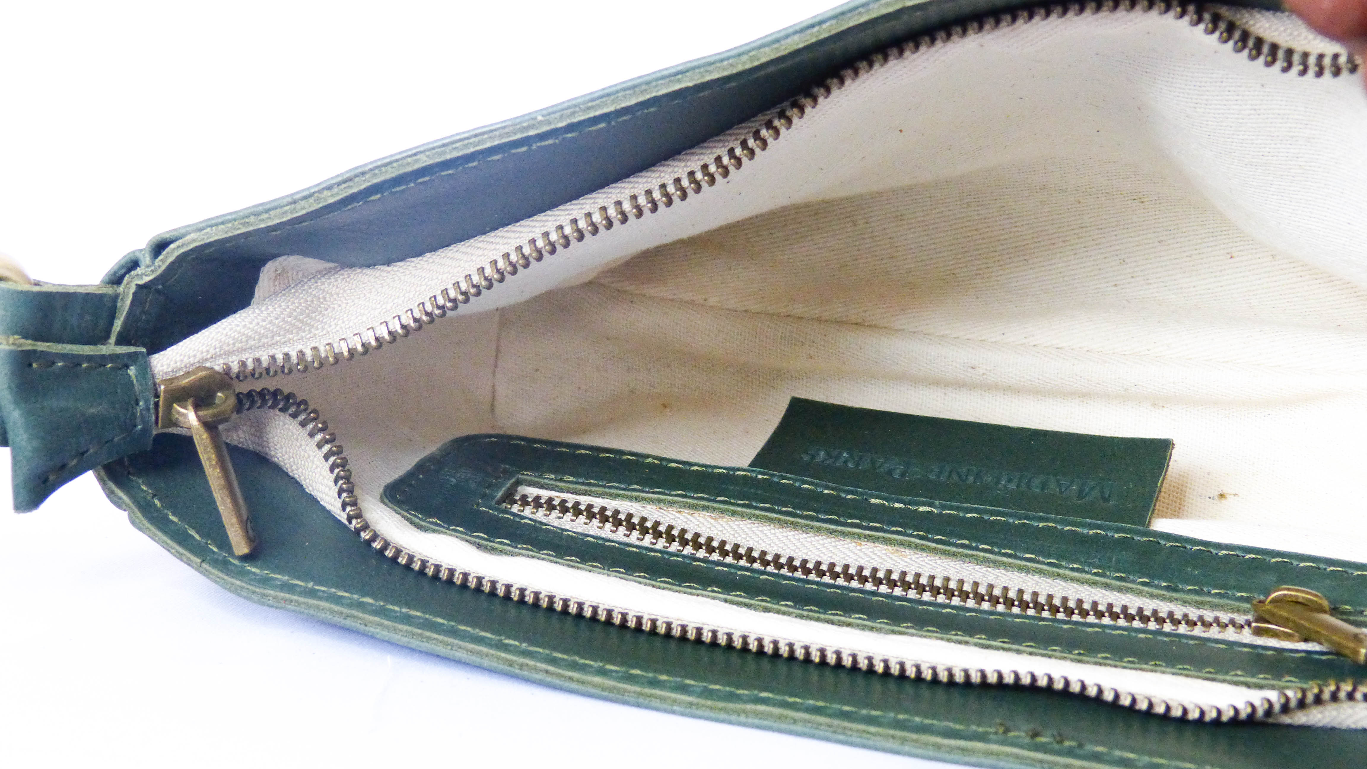 Close-up of the Jessica Leather Purse in Hunter Green, showcasing intricate zipper details on soft leather. Handmade by Ethiopian artisans, features a zippered top, inside pocket, and removable shoulder strap.
