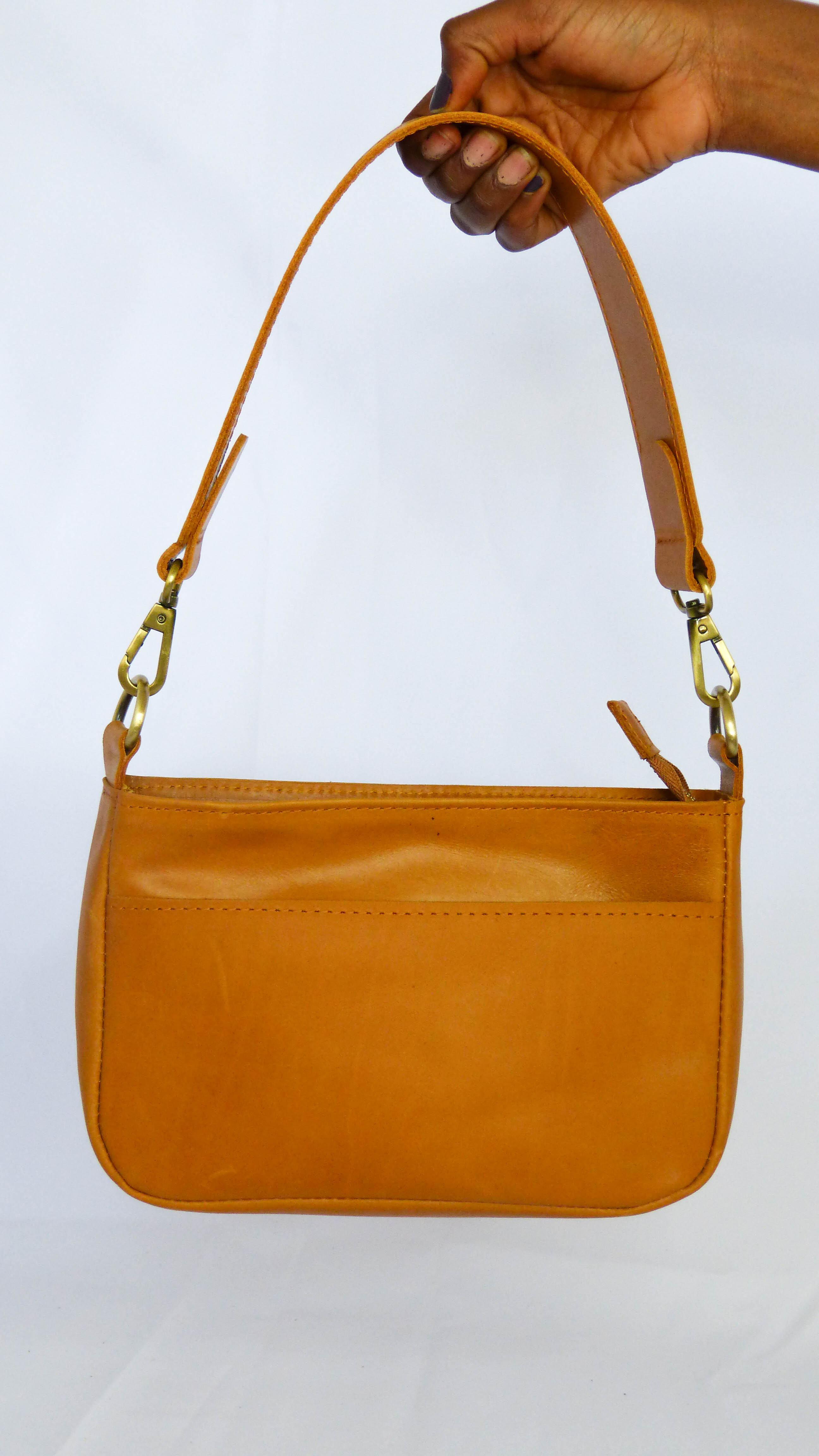 A brown leather Jessica purse with removable shoulder strap, zippered top, inside pocket, and outside phone pocket. Handmade by Ethiopian artisans. Dimensions: 9 x 5.5 x 2.25.