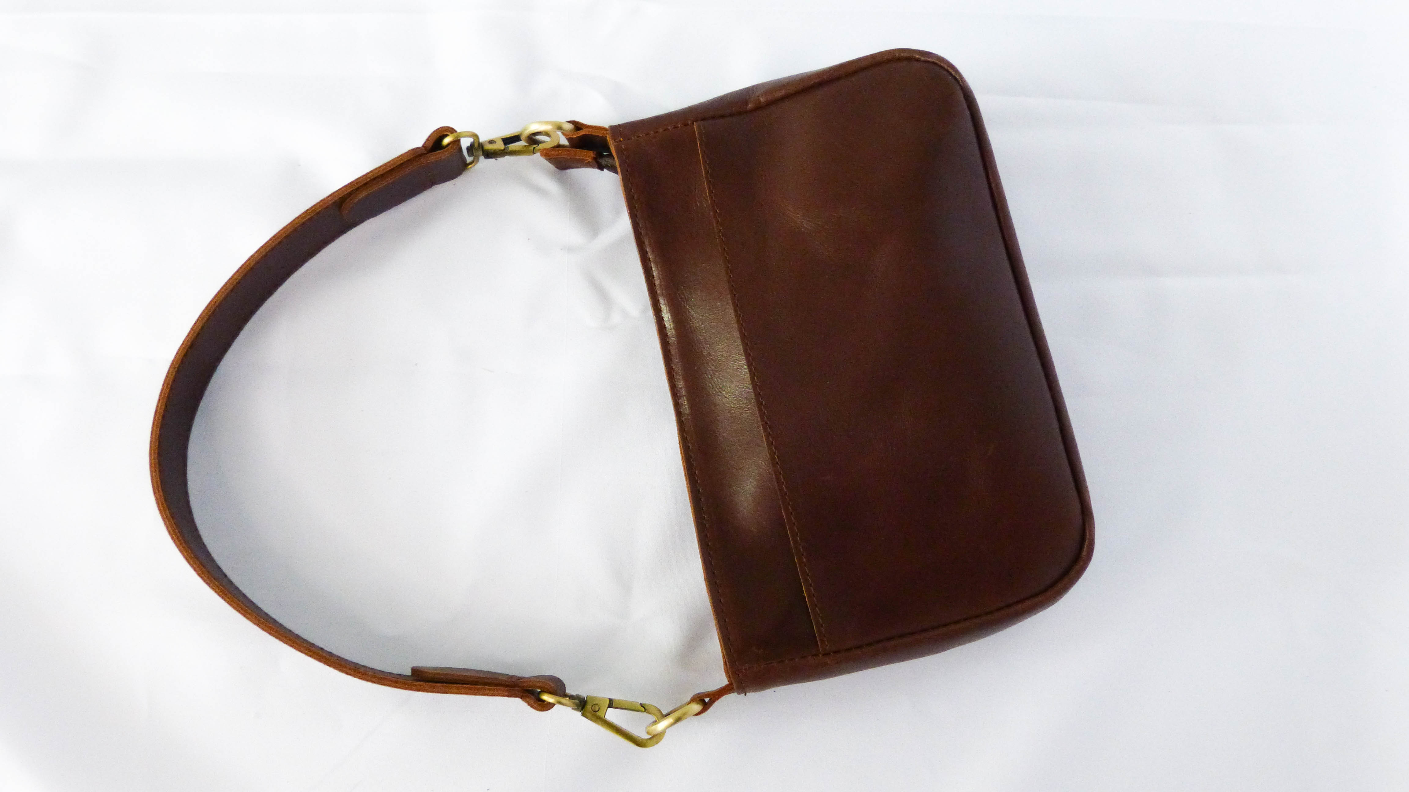 A brown leather Jessica purse with removable strap, zippered top, inside pocket, and outside phone pocket. Handmade by Ethiopian artisans for Madeline Parks Designs.
