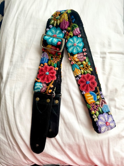 Black Floral Guitar Strap featuring hand-woven, embroidered flowers, adjustable length, leather ends, and a guitar pick pocket for enhanced functionality and style.