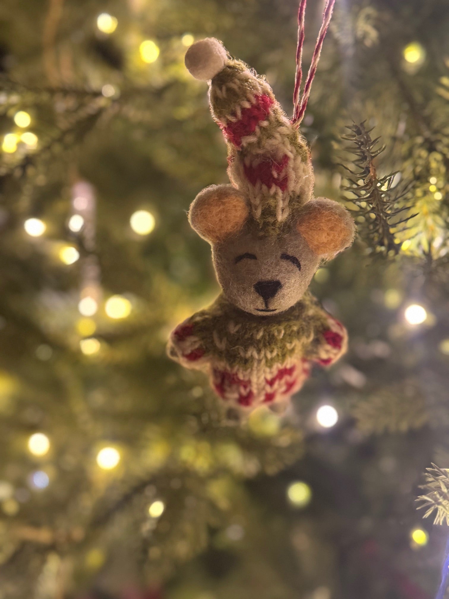 Mouse Ornament wearing a knitted hat and scarf, nestled in a Christmas tree, representing Madeline Parks' artisan-crafted product collection.