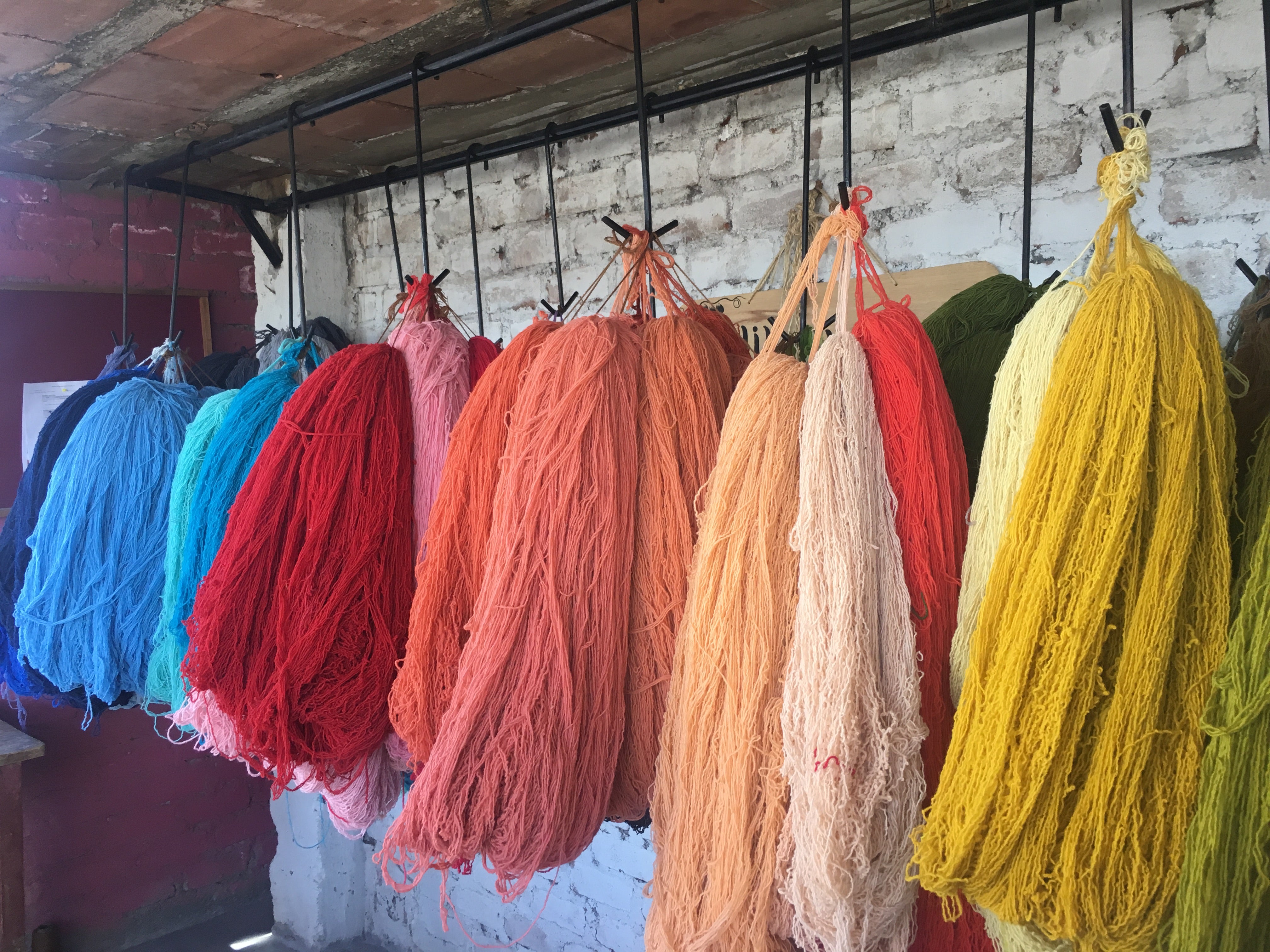 Colorful hand dyed yarn used by fair trade artisans in Peru hanging from the ceiling to dry.