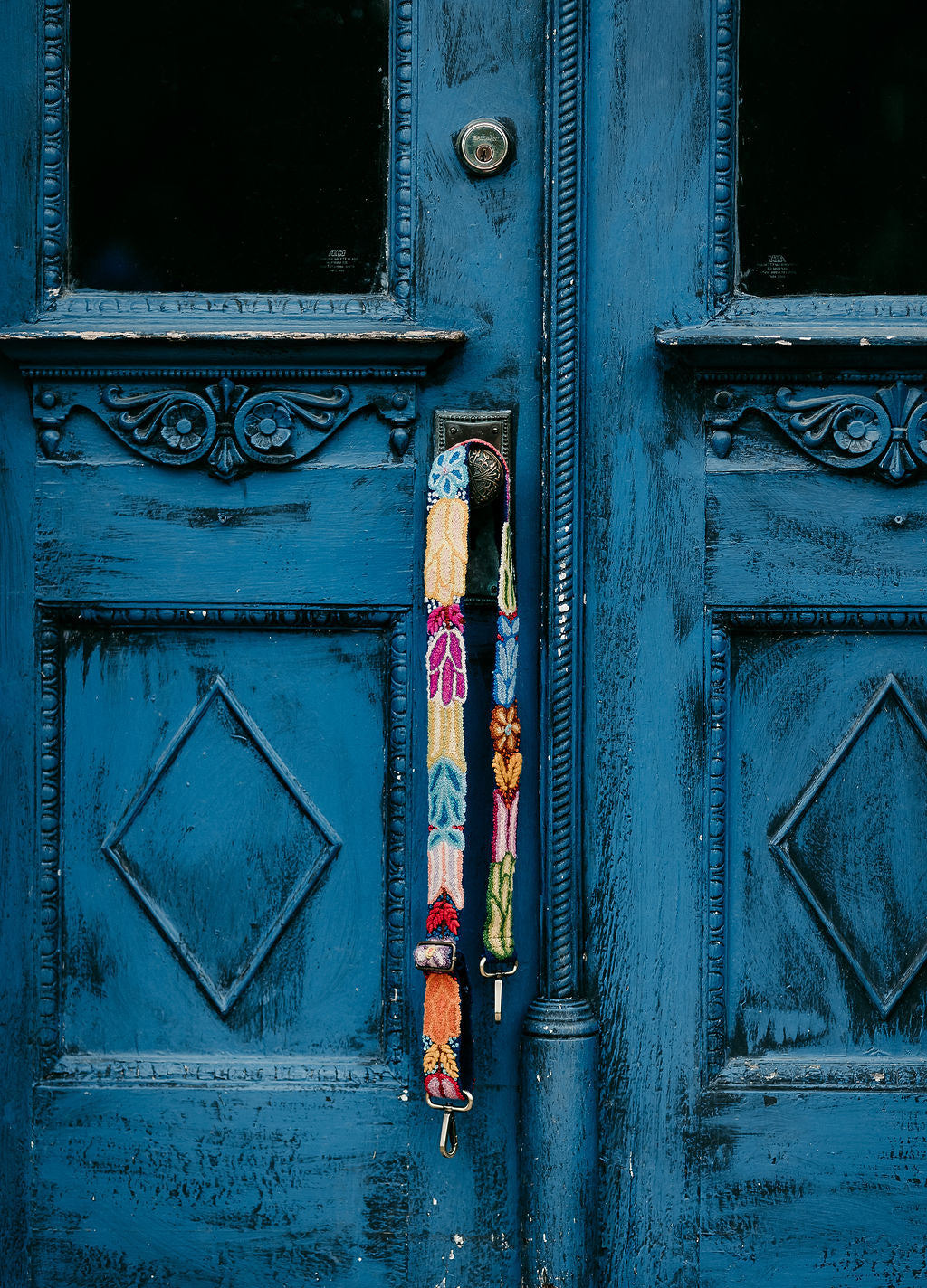 Navy Floral Adjustable Strap displayed hanging around the doorknob of a blue door.
