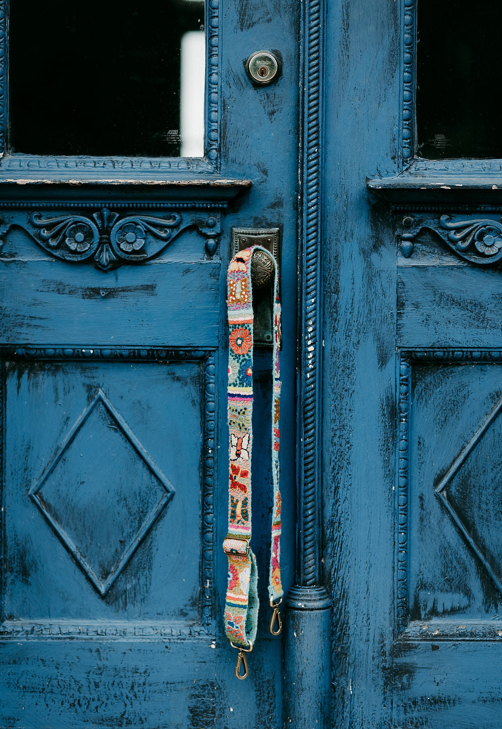 Butterfly Adjustable strap displayed hanging around the doorknob of a blue door.