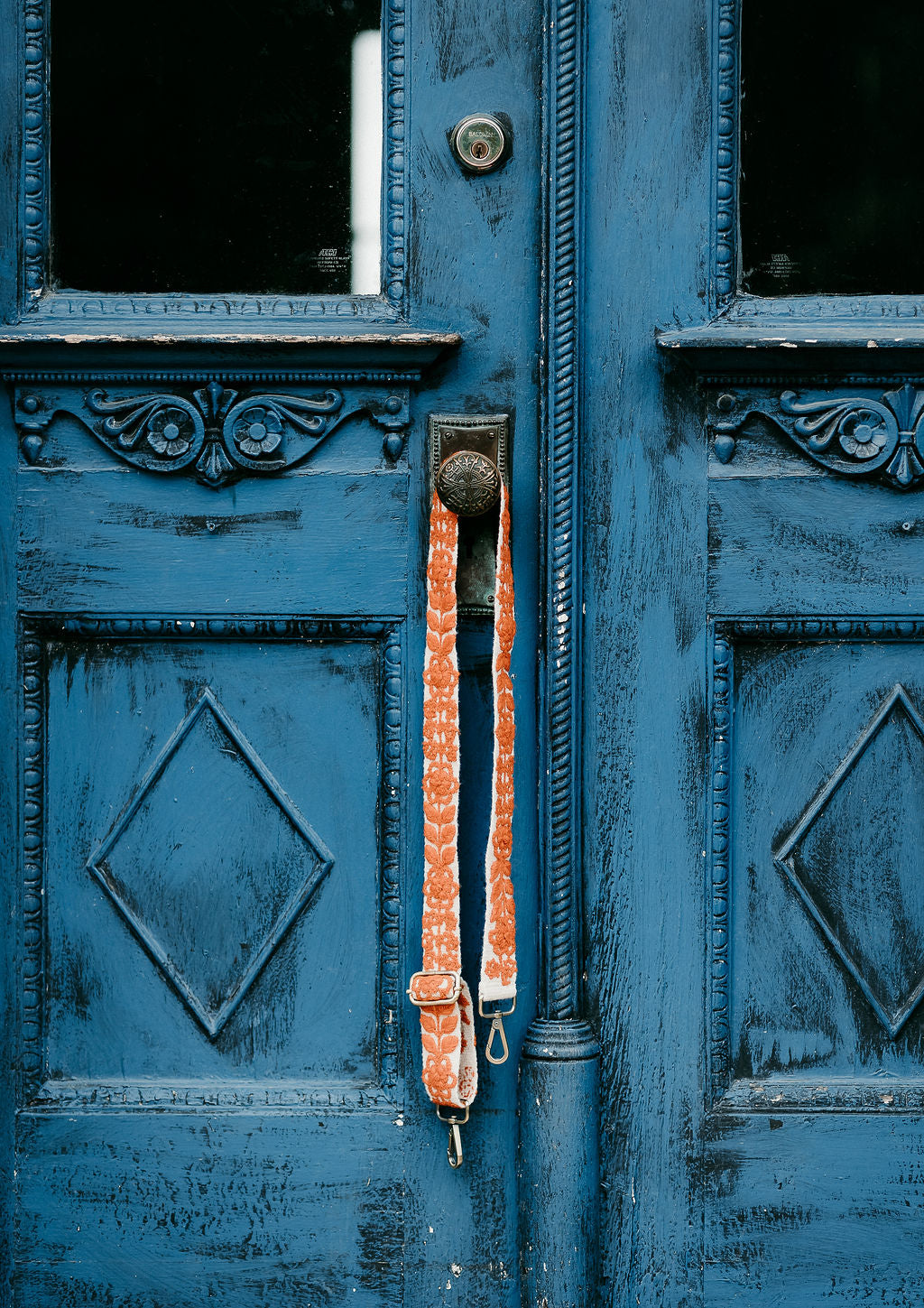 Rachel Adjustable Strap displayed hanging around the doorknob of a blue door.