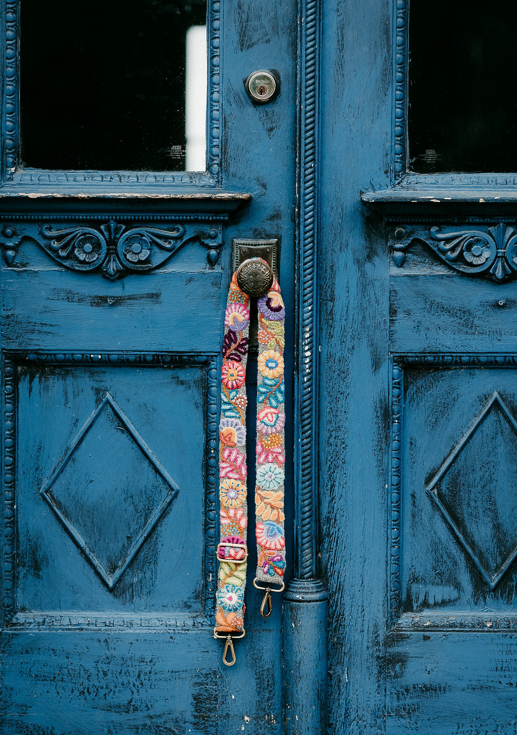 A close-up of a blue embroidered purse strap with a colorful floral and leaves design, handcrafted by Fair Trade artisans in the Andes mountains of Peru. Perfectly pairs with the Anna or Dena purse from Madeline Parks Designs.