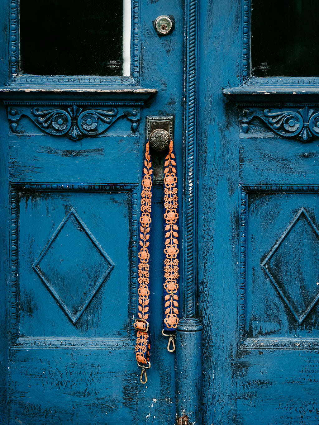 Kenley Adjustable Strap displayed hanging on the doorknob or a blue door.