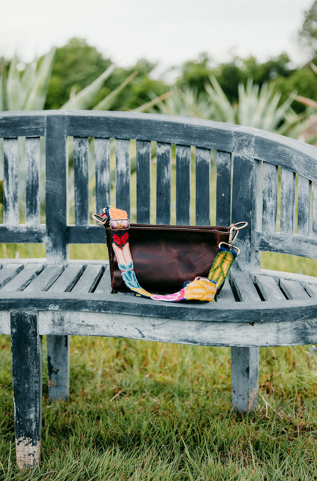 Navy Floral Adjustable Strap attached to a brown leather purse displayed on a bench