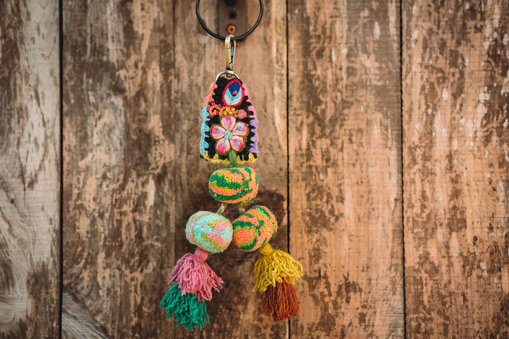A close-up of a colorful tassels hanging on the hook of a wood wall.