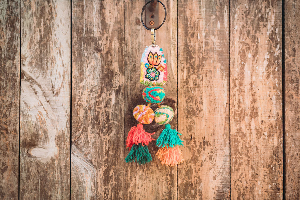 A close-up of a colorful tassels hanging on the hook of a wood wall.